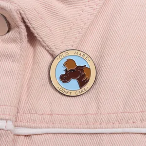 Detailed close-up of a round enamel horse pin on pink denim fabric background