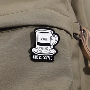 Gros plan d'un pin's en émail tasse à café noir et blanc sur tissu en toile