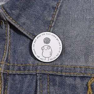 Close-up of a white enamel cartoon badge pinned to a stylish blue denim jacket collar