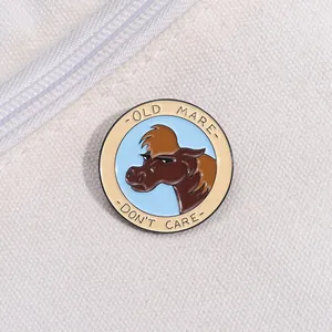 Close-up of a circular enamel horse pin with Old Mare Don't Care slogan on white canvas