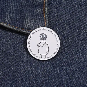 Detail of round enamel lapel pin with minimalist illustration on dark denim fabric