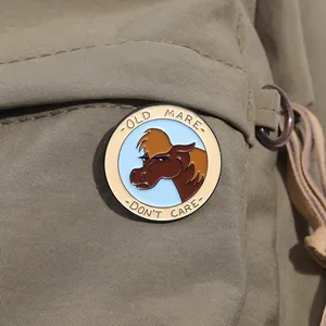 Close-up of Old Mare Don't Care enamel pin attached to a khaki canvas tote bag