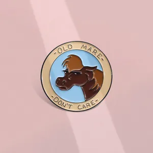 Detail of round enamel lapel pin with Old Mare Don't Care slogan and metal finish