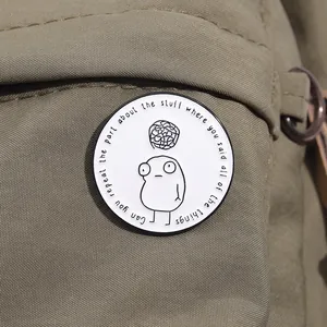 Detail of round enamel lapel pin with minimalist illustration on green canvas bag
