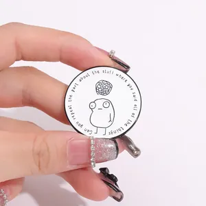 Close-up of enamel lapel pin with funny quote and cartoon character held by hand