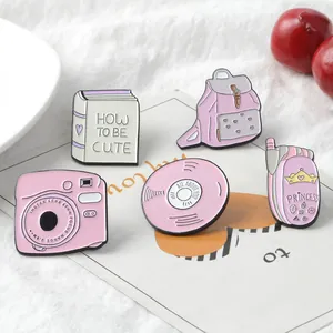 Five-piece pink enamel pin set with cute book, camera, and backpack cartoon designs