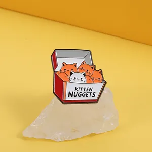 Gros plan du pin's émaillé Kitten Nuggets sur pierre décorative fond jaune vif