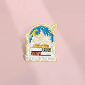 Enamel book pin with snow mountains and dragons for reading enthusiasts on pink background