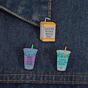Drei bunte Emaille-Anstecknadeln mit spanischem Text auf blauem Jeansstoff