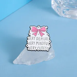 Detailed shot of cloud enamel pin with pink bow and quotes on white mineral stone
