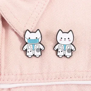 Close-up of cute white cat doctor enamel pins on pink denim fabric background