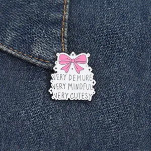 Pink bow enamel pin with Very Demure Very Mindful Very Cutesy quote on denim background