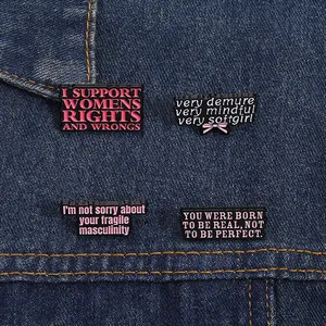 Nahaufnahme von feministischen Emaille-Pins auf blauem Jeansstoff als Taschen-Deko