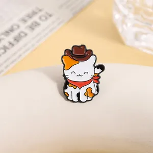 Détail macro du pin's chat calicot en émail avec chapeau de cowboy et foulard rouge