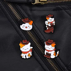 Détail de quatre broches en émail de chat calicot cowboy sur une veste en cuir noir