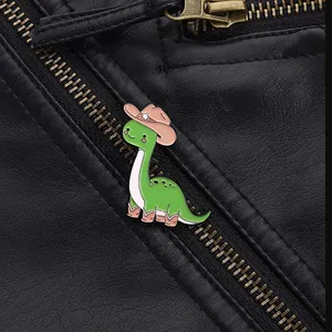 Detail of green dinosaur enamel pin with cowboy hat on black leather jacket lapel
