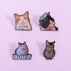 Detailed view of four funny meme cat enamel pins with 'WHAT?!' and 'HUH?!' text expressions