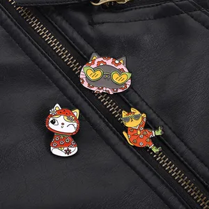 Detailed close-up of three colorful cartoon cat enamel pins on a black leather jacket
