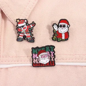 Close-up of dabbing Santa Claus and Merry Christmas text enamel pins on pink denim