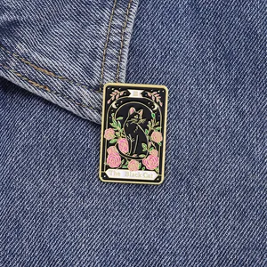 Detail of tarot style enamel pin with black cat and roses on a denim jacket background