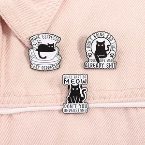Three enamel pins with funny cat quotes pinned on pink denim fabric material