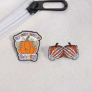 Detail of Halloween enamel pins with skeleton hands and pumpkin design on white canvas bag