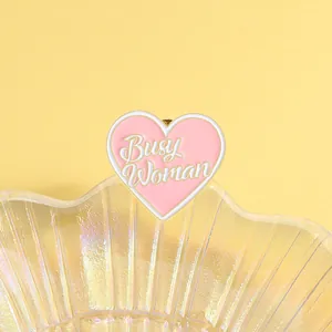Macro shot of Busy Woman heart enamel pin on iridescent shell tray accessory