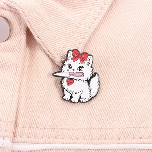 Close-up of white cat enamel pin with red bow and knife on pink denim jacket collar