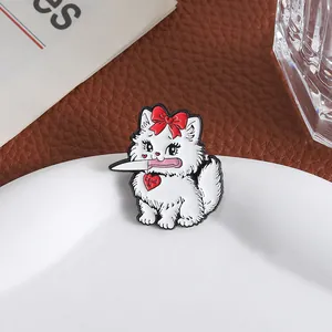 Detail of white cat enamel pin with red bow and knife on a white ceramic plate