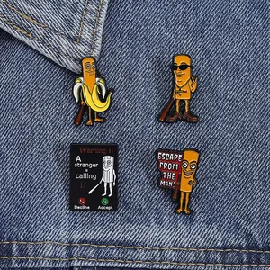 Detail of four dark humor enamel pins with cartoon characters on denim fabric background