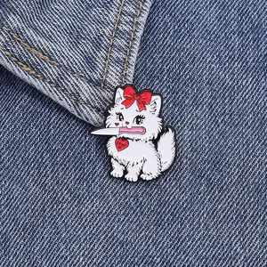 Cute white cat enamel pin with a red bow and silver dagger on denim fabric