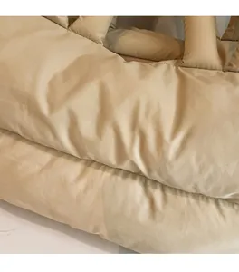 Detail of soft quilted texture and padded material on the beige puffer tote bag
