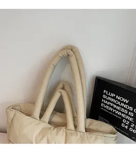 Detail of beige quilted puffer tote bag featuring double handles and zipper closure