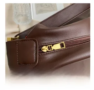 Close-up of smooth gold-tone zipper and fine stitching on the brown leather tote bag