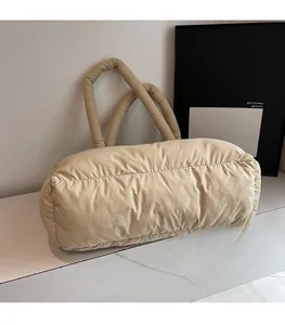 Detail of beige quilted puffer tote bag with thick padded handle and soft texture