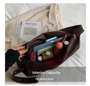 Internal capacity of the dark brown leather tote bag showing books, tablet, and daily items