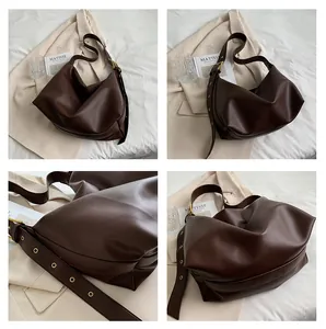 Detail of dark brown pebble leather hobo bag with wide strap and gold hardware