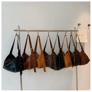 Row of minimalist leather hobo bags in various colors on a silver metal display rack