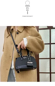 Detail of black shell-shaped bag featuring woven texture and adjustable shoulder strap