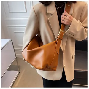 Detail of caramel faux leather tote bag showing wide strap and golden metal buckle