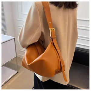 Detail of adjustable wide shoulder strap with golden buckle on caramel tote bag