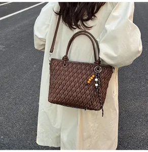 Close-up of brown woven texture tote bag with circular handles on trench coat model