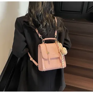 Pink mini PU leather backpack detail with plush bear charm and golden logo on black blazer