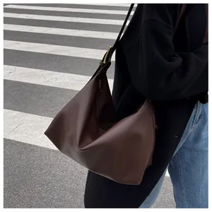 Detail of dark brown leather hobo bag with adjustable gold buckle on outdoor street