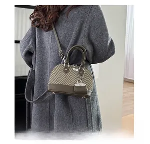 Detail of herringbone fabric and green leather shell bag on a grey wool coat