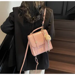 Pink PU leather handbag with metal buckle and teddy bear charm shown on a model