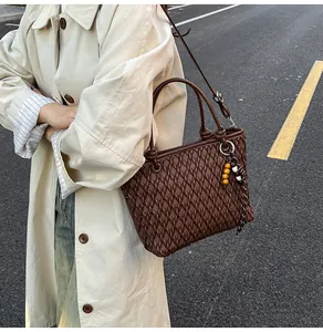 Detailed view of dark brown woven handbag featuring a unique wooden bead tassel pendant