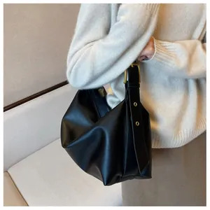 Detail of black pebbled leather tote bag with decorative gold metal hardware on strap