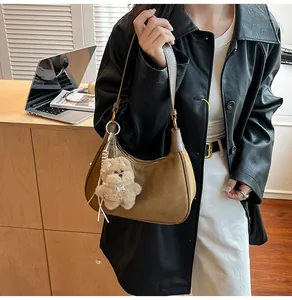 Close-up of brown suede shoulder bag with a cute plush dog pendant and leather strap