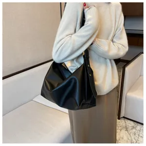 Close-up of large black matte leather tote bag with elegant golden hardware and buckle